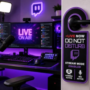 May include: A black and purple door hanger with the text LIVE NOW DO NOT DISTURB, STREAM MODE ENABLED, CAMERA ACTIVE, and MIC ACTIVE. The sign features a purple Twitch logo and icons for a camera and microphone, hanging on a black door handle.