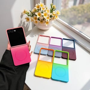 May include: A collection of foldable phone cases featuring a magnetic charging ring on the back. The cases come in various gradient colour combinations, including pink, orange-yellow, blue-purple, and green-blue, designed for a folding smartphone.