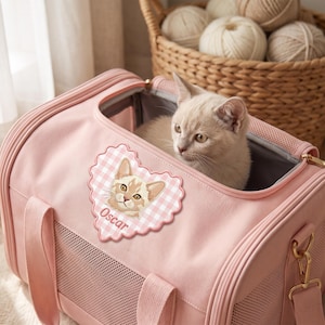 Puede incluir: Un transportín para mascotas de color rosa claro con paneles de ventilación de malla y un parche en forma de corazón con un patrón de cuadros vichy rosa y blanco, una ilustración de un gato y el nombre Oscar en letra cursiva, con un gato dentro.