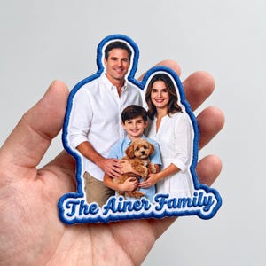 Pode incluir: Um emblema bordado personalizado com uma fotografia impressa de uma família de três pessoas e um pequeno cachorro castanho. O emblema tem uma borda azul costurada e o texto The Ainer Family em letra cursiva azul na parte inferior.