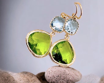 May include: A pair of drop earrings featuring faceted, light blue square-cut stones at the top and larger, pear-shaped, vibrant lime green stones at the bottom. Each stone is set in a gold-toned metal frame with a textured, organic edge.