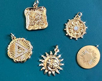May include: Five gold-toned pendants with different designs. The pendants include a square with a detailed design, a round pendant with a swirl design, a round pendant with a triangle and a starburst design, a sun pendant with a face and a starburst design, and a round pendant with a sunburst design.