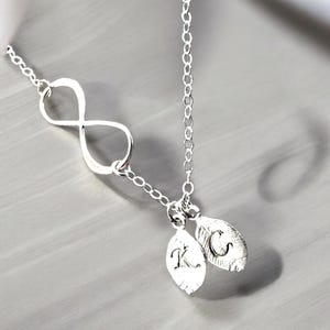 May include: A silver infinity necklace with two small silver leaf charms with the initials K and C engraved on them.