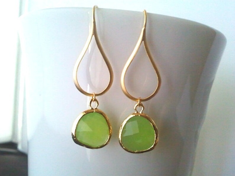 Puede incluir: Pendientes de gota de oro con detalles de piedras preciosas verde claro.