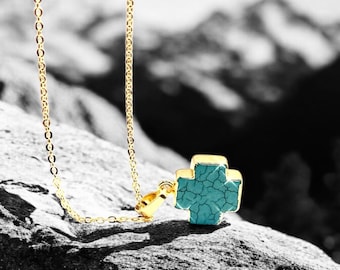 May include: A gold chain necklace with a turquoise cross pendant. The cross is set with small clear stones.