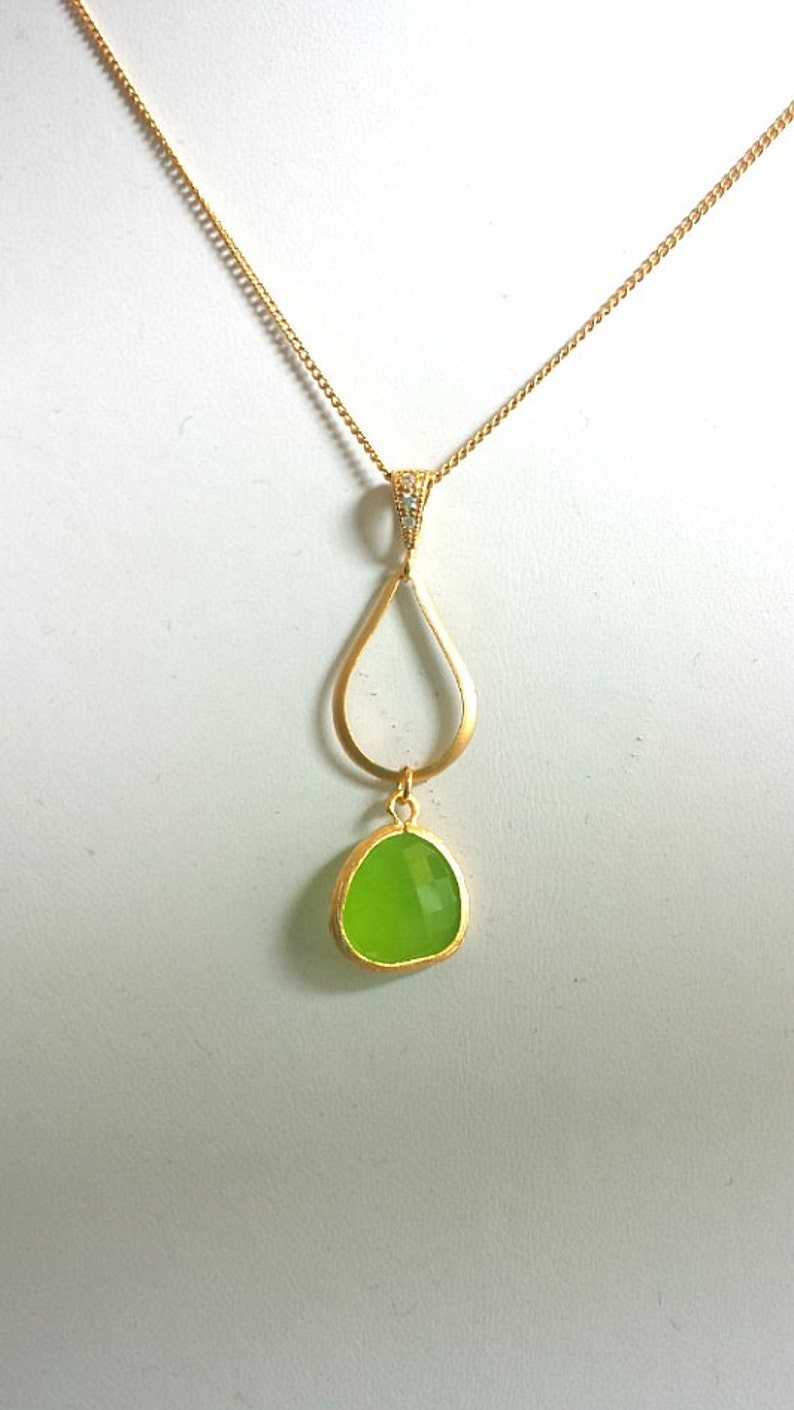 Puede incluir: Un collar de cadena de oro con un colgante en forma de l&aacute;grima. El colgante tiene una piedra preciosa verde y una forma de l&aacute;grima dorada m&aacute;s peque&ntilde;a en su interior.