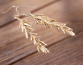 May include: A pair of gold-tone earrings with a delicate, leafy design. The earrings are dangle style and feature a cluster of small, leaf-shaped charms.
