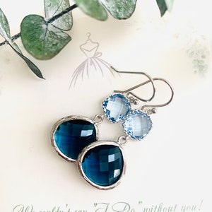 May include: A pair of bridesmaid earrings with a teardrop-shaped dark blue crystal and a smaller light blue crystal. The earrings are silver-toned and have a simple design. The text "We couldn't say "I Do" without you! Thank you for being my Bridesmaid." is written on the card.