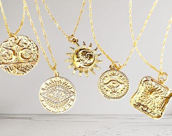 May include: Five gold necklaces with different pendants. The pendants include a sun and moon, an evil eye, a square design, and two different circular designs.