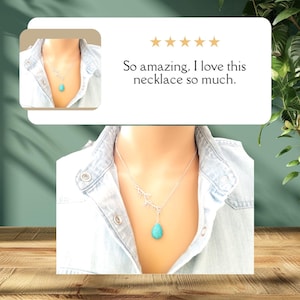 May include: A silver necklace with a turquoise teardrop pendant and a delicate branch design. The necklace is worn by a person with a light blue denim shirt.