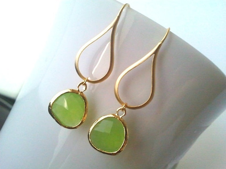 Puede incluir: Pendientes de gota de oro con detalles de piedras preciosas verde claro.