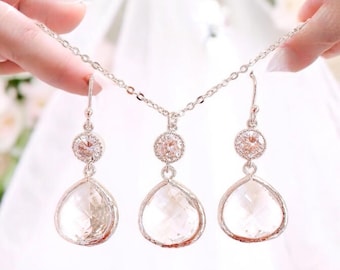May include: A silver necklace and earrings set with clear teardrop-shaped crystals and smaller round crystals.