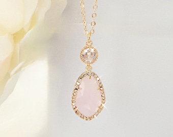 Puede incluir: Un delicado collar de cadena dorada con un colgante ovalado rosa acentuado con diamantes de imitación transparentes. El colgante está rodeado por un halo de diamantes de imitación más pequeños.