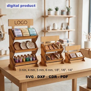 May include: Three tiered wooden display stands for retail products, featuring a top header labeled LOGO. The stands hold soap bars, circular coasters, small glass bottles, leather keychains, and jewelry boxes. Text includes 3 mm, 4 mm, 5 mm, 6 mm, 1/8", 1/6", 1/4", SVG, DXF, CDR, PDF.