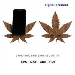 Op de afbeelding: Een bruine houten telefoonstandaard in de vorm van een cannabisblad, getoond met een zwarte smartphone. De tekst digital product is zichtbaar, samen met de maten 3 mm, 4 mm, 5 mm, 6 mm, 1/8", 1/6", 1/4" en bestandsformaten SVG, DXF, CDR, PDF.