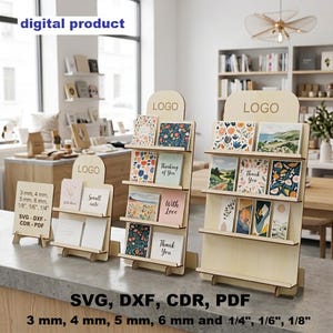 May include: Three light-coloured wooden display stands for greeting cards, each featuring a top section labelled LOGO. The stands hold various illustrated cards with text like Thank You and Thinking of You. Includes text: digital product, SVG, DXF, CDR, PDF, 3 mm, 4 mm, 5 mm, 6 mm, 1/8 inch, 1/6 inch, 1/4 inch.