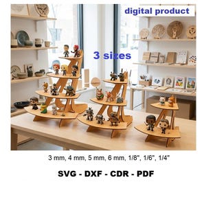 Op de afbeelding: Drie houten displays met meerdere niveaus voor kleine beeldjes, aangeduid als digitaal product in 3 maten. De tekst bevat 3 mm, 4 mm, 5 mm, 6 mm, 1/8", 1/6", 1/4" en bestandsformaten SVG, DXF, CDR, PDF. Afwerking in licht hout.