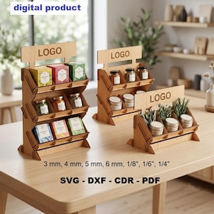 Peut inclure: Trois présentoirs en bois à plusieurs niveaux pour produits de détail, avec un en-tête portant le texte LOGO. Les supports sont conçus pour des épaisseurs de matériau de 3 mm, 4 mm, 5 mm, 6 mm, 1/8", 1/6", 1/4", disponibles en formats SVG, DXF, CDR et PDF.