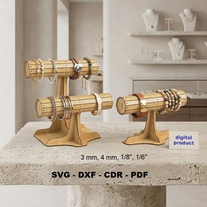 Könnte beinhalten: Zwei helle Schmuckständer aus Holz mit zylindrischen Stangen für Armbänder. Die Ständer haben horizontale Lamellen und stabile Sockel. Der Text umfasst digital product, 3 mm, 4 mm, 1/8", 1/6", SVG, DXF, CDR und PDF. Die Ständer sind mit verschiedenen Armbändern bestückt.