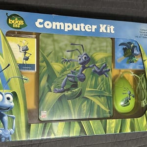 May include: A Disney Pixar A Bug's Life computer kit in original packaging. The set includes a light green computer mouse with an ant graphic, a mouse pad featuring an ant on green leaves, a diskette case, and ten 3.5-inch diskette labels.
