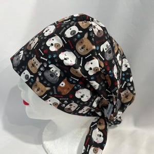 May include: A black scrub hat with a colourful pattern of dogs and bones. The hat is tied at the back with a long tie.