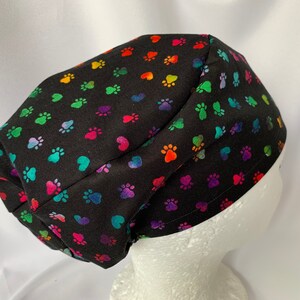 May include: Black scrub hat with a colourful paw print and heart pattern.