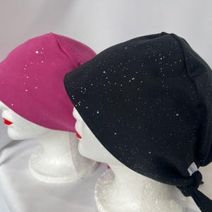 May include: Two surgical caps with a sparkly design. One cap is pink and the other is black.