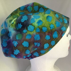 May include: A blue, green, and purple tie-dye scrub hat with a white trim. The hat has a blue and green pattern with white dots.