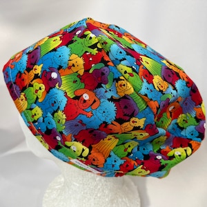 May include: A colorful surgical scrub hat with a pattern of cartoon dogs in various colors and poses. The hat is made of a soft, comfortable fabric and is perfect for healthcare professionals.