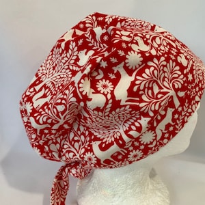 May include: Red and white scrub hat with a woodland animal print. The hat has a tie at the back.