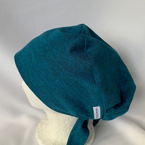 May include: Teal blue scrub hat with a tie back and a small white label that says "Scrub Caps".