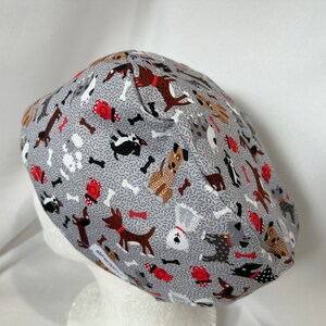 May include: Grey scrub hat with a pattern of various dog breeds, bones and red fire hydrants.