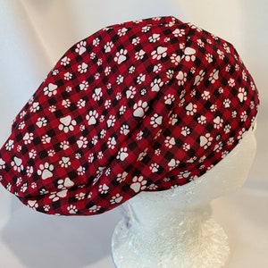 May include: Red and black buffalo check scrub hat with white paw prints.