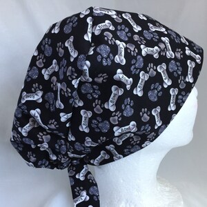 May include: Black scrub hat with a white paw print and bone pattern. The pattern includes the word "BONE" repeated throughout.