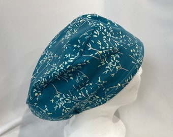 Könnte beinhalten: Eine tealblaue OP-Mütze mit einem weißen und gelben Blumenmuster. Die Mütze ist aus einem weichen, bequemen Stoff gefertigt und hat einen Bindeverschluss.