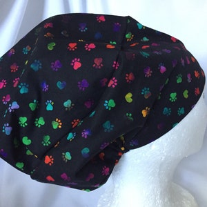 May include: Black scrub hat with a colourful paw print and heart pattern.