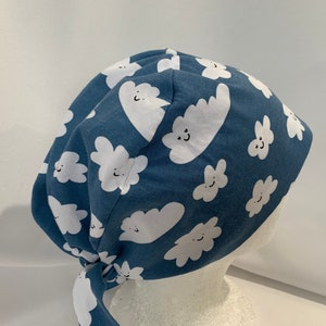 May include: A blue scrub hat with a white cloud pattern. The clouds have smiling faces.