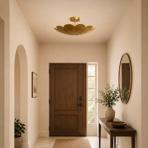May include: A gold-toned flush mount ceiling light fixture featuring a layered, petal-like design that radiates from a central stem. The fixture is mounted to a light-coloured ceiling, providing overhead illumination in a residential entryway.