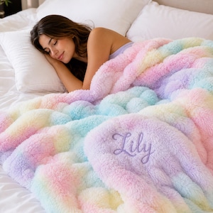 May include: A plush, faux-fur throw blanket featuring a pastel rainbow tie-dye pattern of pink, blue, yellow, and purple. The blanket is embroidered with the name Lily in a cursive purple script font on the bottom right corner of the fabric.