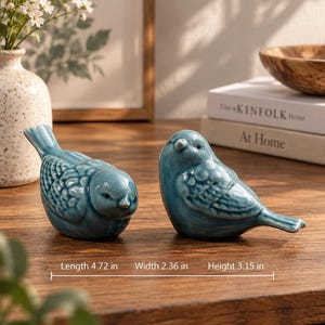 Könnte beinhalten: Zwei glänzende blaue Keramik-Vogelfiguren mit detaillierter Flügelstruktur. Jeder Vogel misst 12 cm in der Länge, 6 cm in der Breite und 8 cm in der Höhe. Die Figuren haben glatte, abgerundete Körper und kleine Schnäbel als Paar.