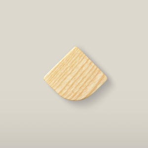 May include: A fan-shaped piece of light-colored wood with a visible natural grain pattern. The object features a flat, smooth surface with a curved bottom edge and two straight sides meeting at a pointed top corner, showcasing a light tan hue.