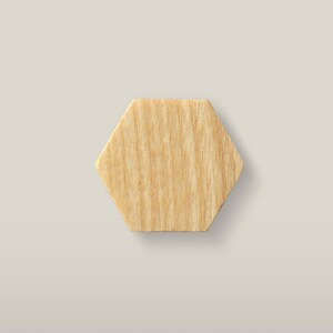Könnte beinhalten: Ein hellbraunes Holzsechseck mit einer sichtbaren natürlichen Maserung. Das Objekt verfügt über sechs gerade Kanten und eine flache Oberfläche, die die organische Textur und die hellbraunen Farbtöne des Holzes in einer geometrischen Form zeigt.