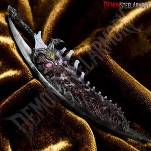 May include: A fantasy dagger featuring a dark, textured blade with organic, vein-like details and a central pink eye-shaped accent. The hilt has a black, twisted handle and a gold-colored emblem. The text DEMONSTEELARMORY is visible in the corner.