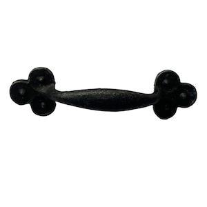 May include: Black metal drawer pull with a curved shape and a decorative clover design on each end.
