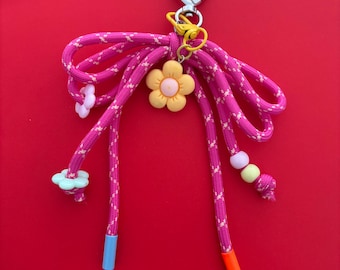 Ciondolo per borsa a forma di fiocco rosa con perline e clip a forma di fiore.