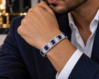 May include: A silver-toned link bracelet featuring rectangular deep blue stones alternating with smaller segments encrusted with tiny clear white stones. The bracelet has a structured, geometric design with a polished metallic finish.