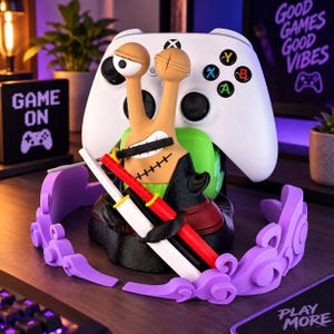 Può includere: Una statuetta a forma di lumaca color marrone chiaro con un occhio grande e una bocca cucita che tiene una spada nera tra i denti. Indossa un cappotto nero e tiene due spade aggiuntive, una bianca e una rossa, davanti a un controller Xbox bianco.
