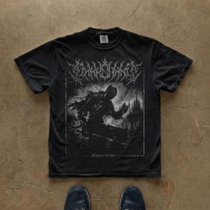 Könnte beinhalten: Ein schwarzes Kurzarm-T-Shirt mit einem weißen Grafikdruck eines Ritters in Rüstung vor einer Burg. Der Text oben ist in einer stilisierten gotischen Schrift gehalten und der Text unten lautet Prepare To Die in kleinerer Schrift.