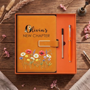 Può includere: Un taccuino arancione con chiusura dorata, con il testo Olivia's NEW CHAPTER e una stampa floreale colorata di papaveri e margherite. Il taccuino è contenuto in una scatola regalo arancione insieme a una penna nera sottile e una penna arancione.