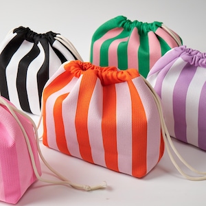 Può includere: Una collezione di cinque sacchetti con coulisse realizzati in tessuto a rete, ognuno caratterizzato da strisce verticali in varie combinazioni di colori, tra cui nero e bianco, arancione e rosa, verde e rosa, viola e bianco, e rosa e bianco.
